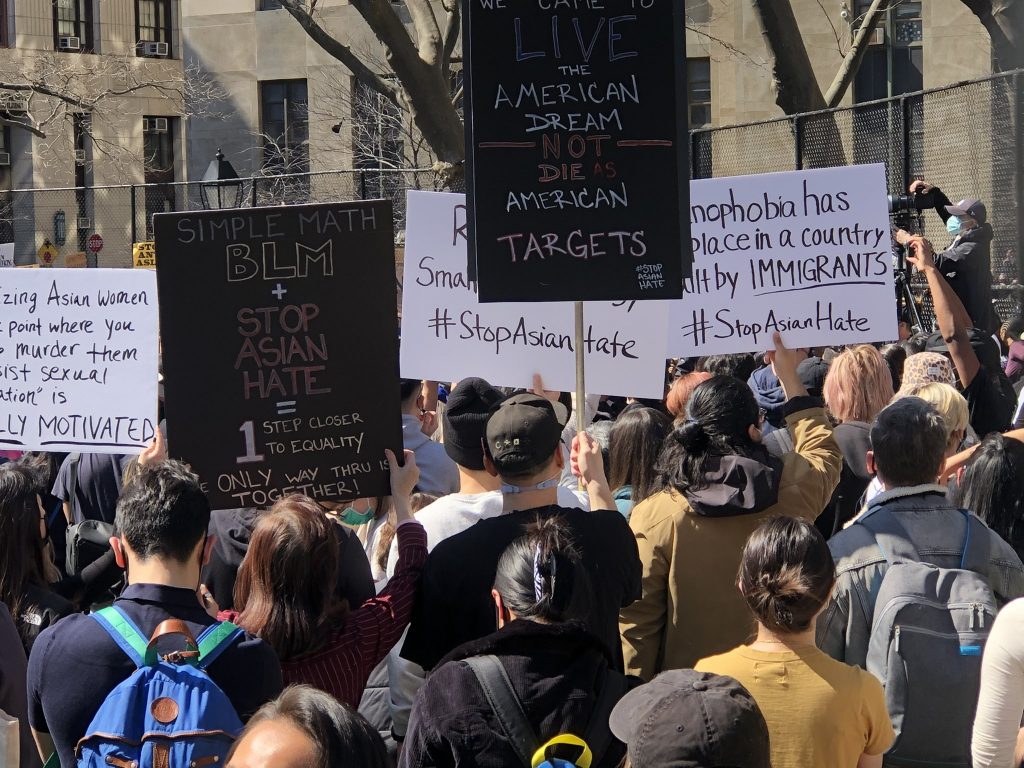 A crowd at a NYC rally against Asian Hate. The sign in the foreground says "Simple Math: BLM + Stop Asian Hate =1 Step Closer to Equality