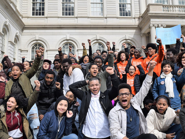 A large group of students gather in front of a capital building to advocate for counselors instead of policing in schools.