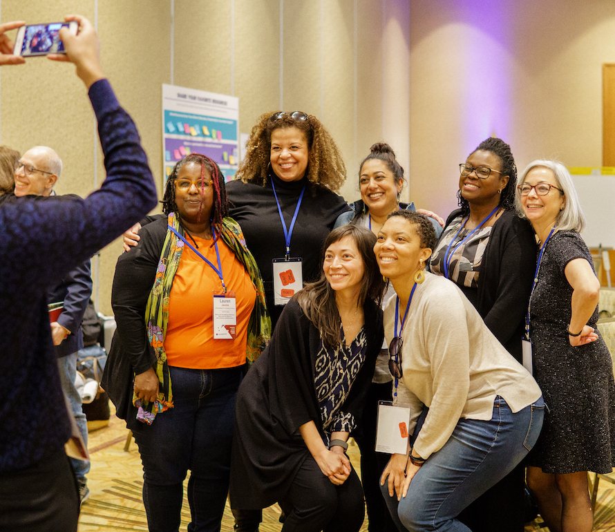 A group of people gather together to take a photo with an iPhone