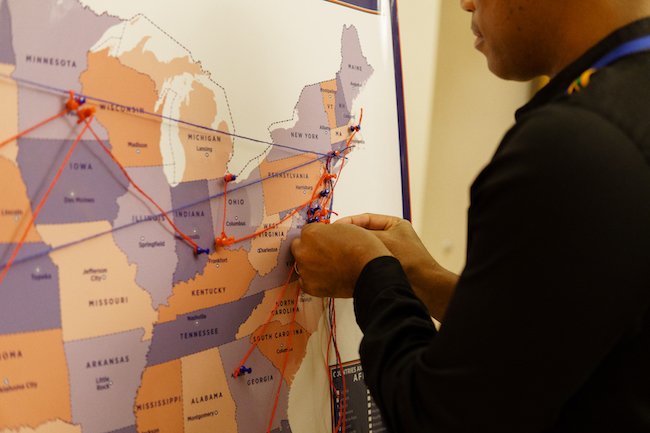 A person pins a string onto a map of the US