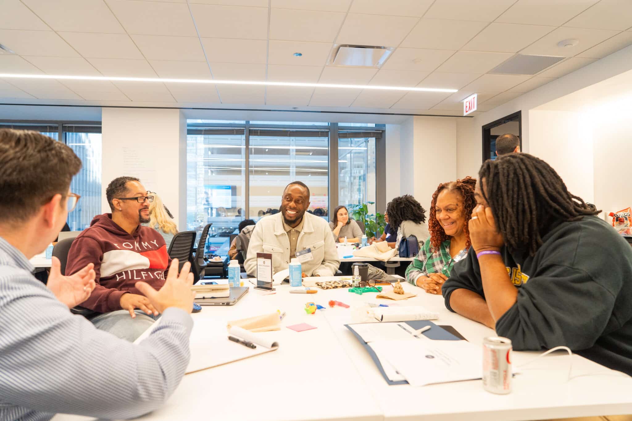 Five people sit at a table in an office and talk.