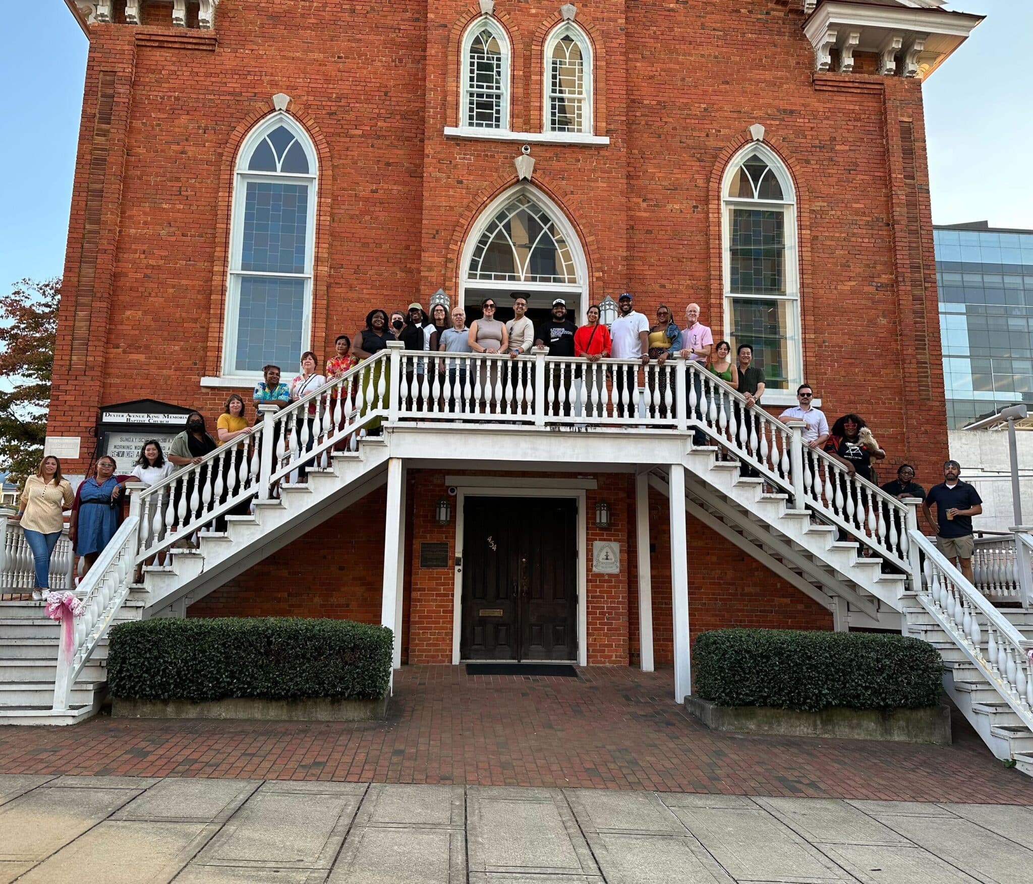 Surdna staff stand on staircases in front of a red brick church.